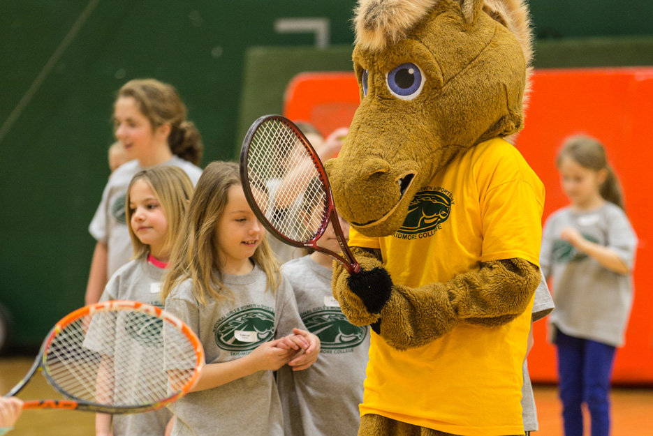 Skidmore's mascot plays tennis with young girls learning sports