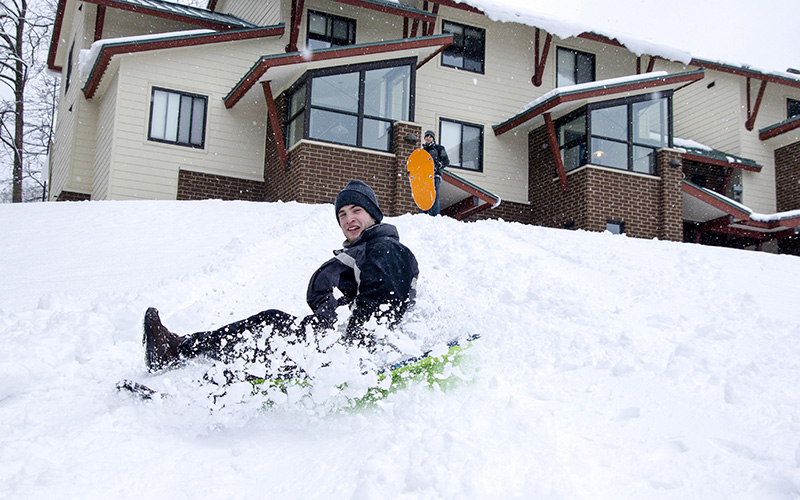 Male student sledding on Skidmore's campus