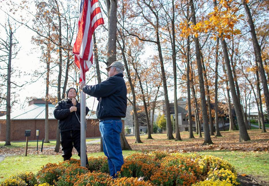 Raymond Apholz and Bob Pierce raise an American flag.
