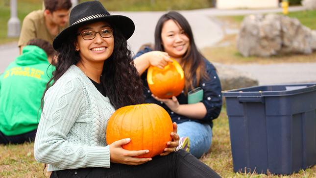 College student carving a pumpkin