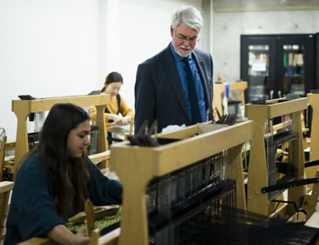 Making a dress, Lucy Beizer '19 demonstrates tapestry weaving to Skidmore President Philip A. Glotzbach. 