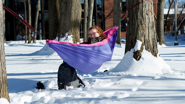 Skidmore student hangs in a hammock in the winter 