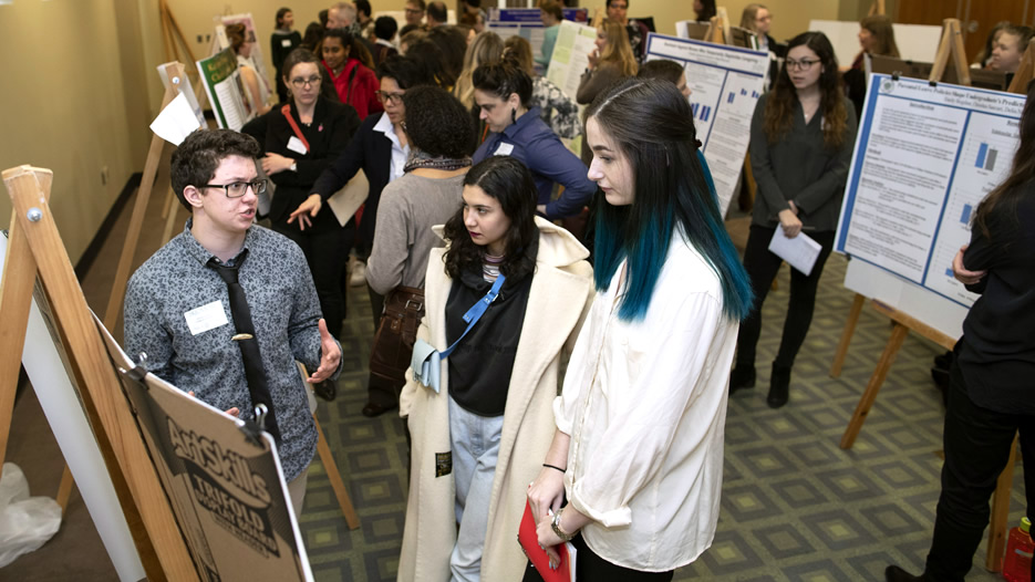 Students attend poster presentations at feminist studies conference