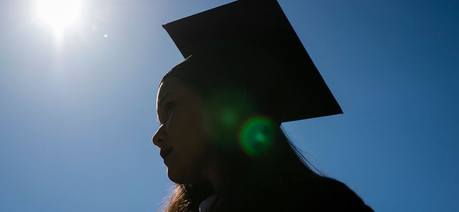 A silhouette of a college graduate in her cap and gown 