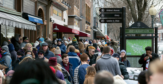A crowd of people fill the sidewalks of Saratoga Springs, NY