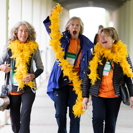 Three+women+wave+yellow+feather+boas+and+laugh+on+their+way+to+a+Skidmore+reunion+event