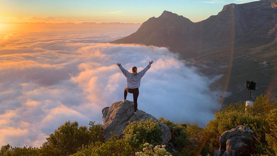 A student studying abroad in South Africa has her photo taken overlooking a mountain range