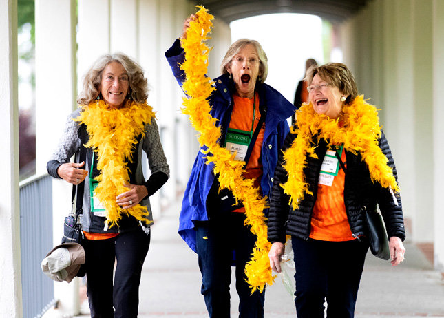 Three members of the Class of 1969 at Skidmore College wave feather boas