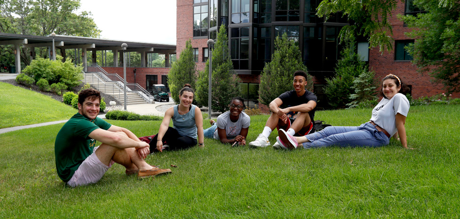Five Skidmore College sit outside on the grass 