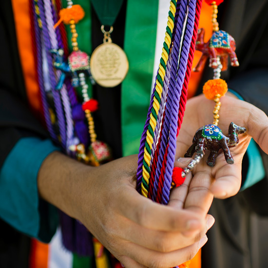 A graduate shows off a handful of colorful graduation regalia items