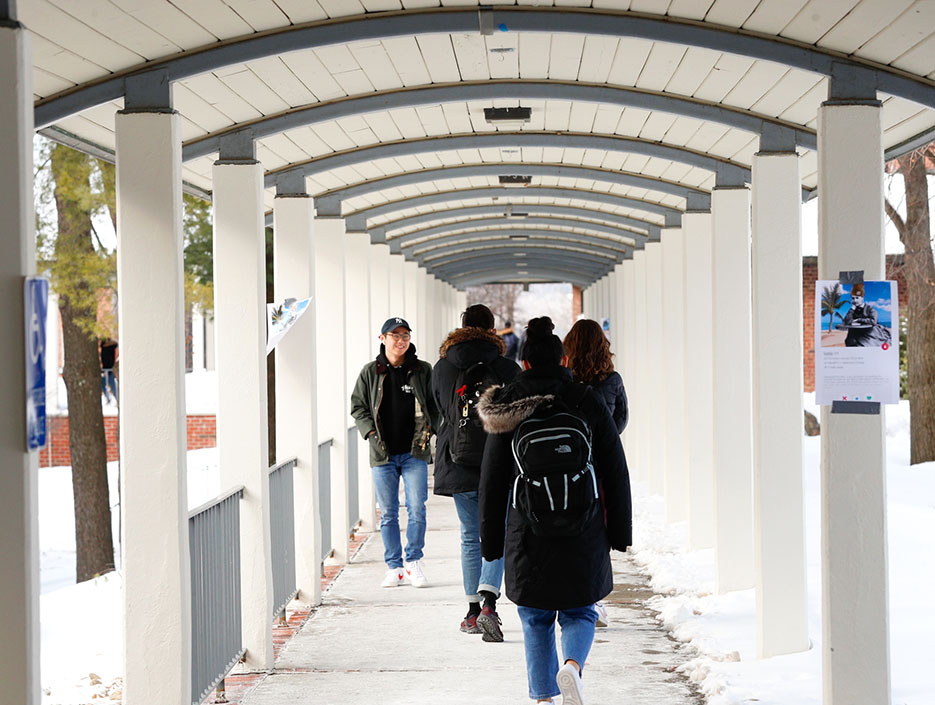 Students walk between classes on a covered walkway near Case Center. 