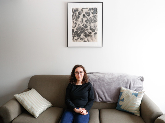 Emily Theisen '22 in her room with a 1990 untitled lithograph by Julian Lethbridge.