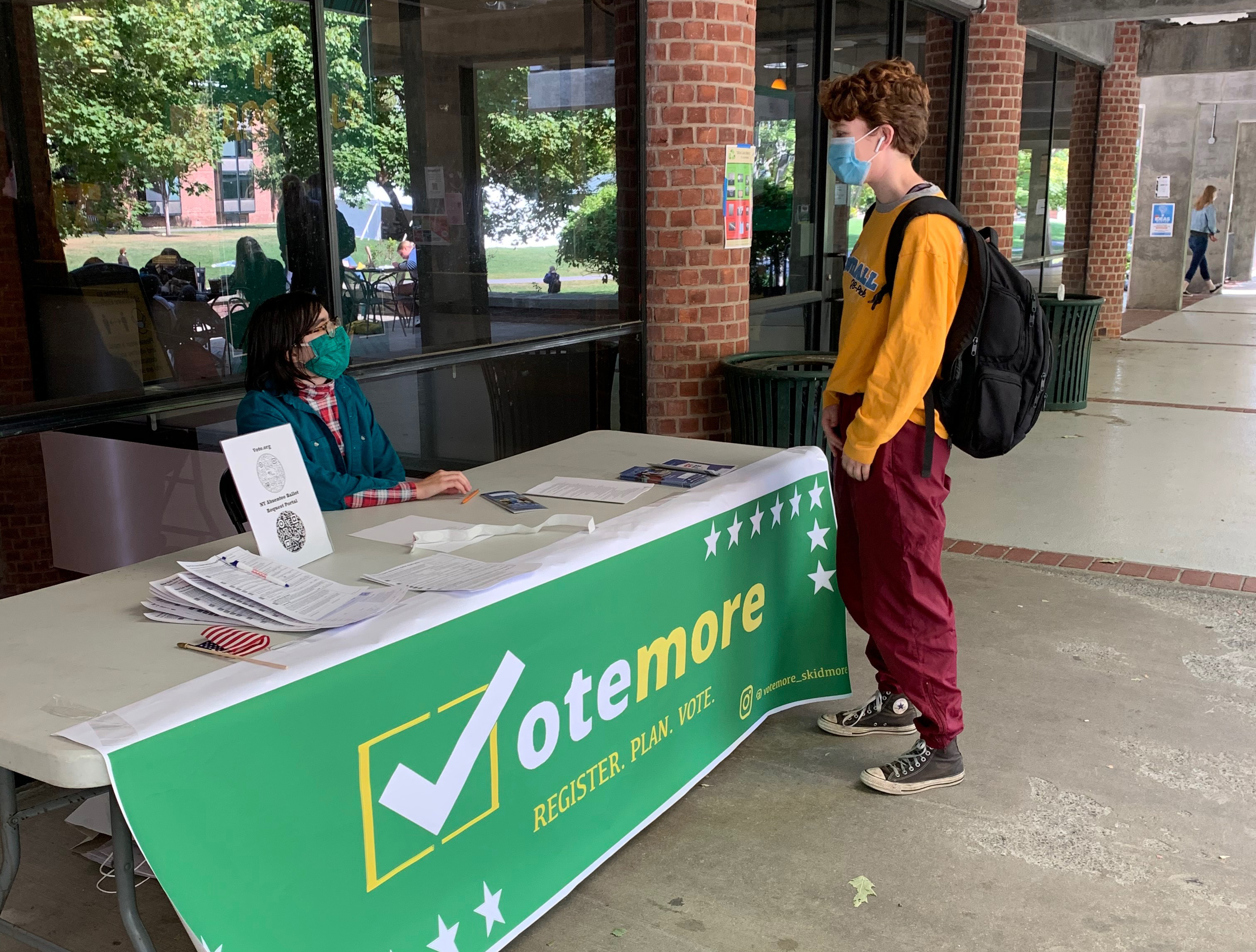 Two students at a voting information desk on campus