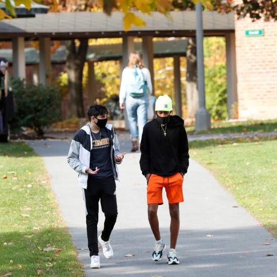 Two male students walk on a college campus