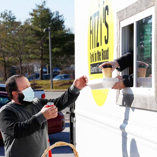 An+employee+receives+a+meal+from+a+food+truck+on+campus.