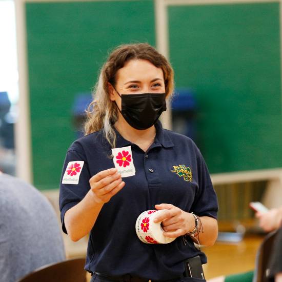 Student wearing a facemask while giving out vaccination stickers 