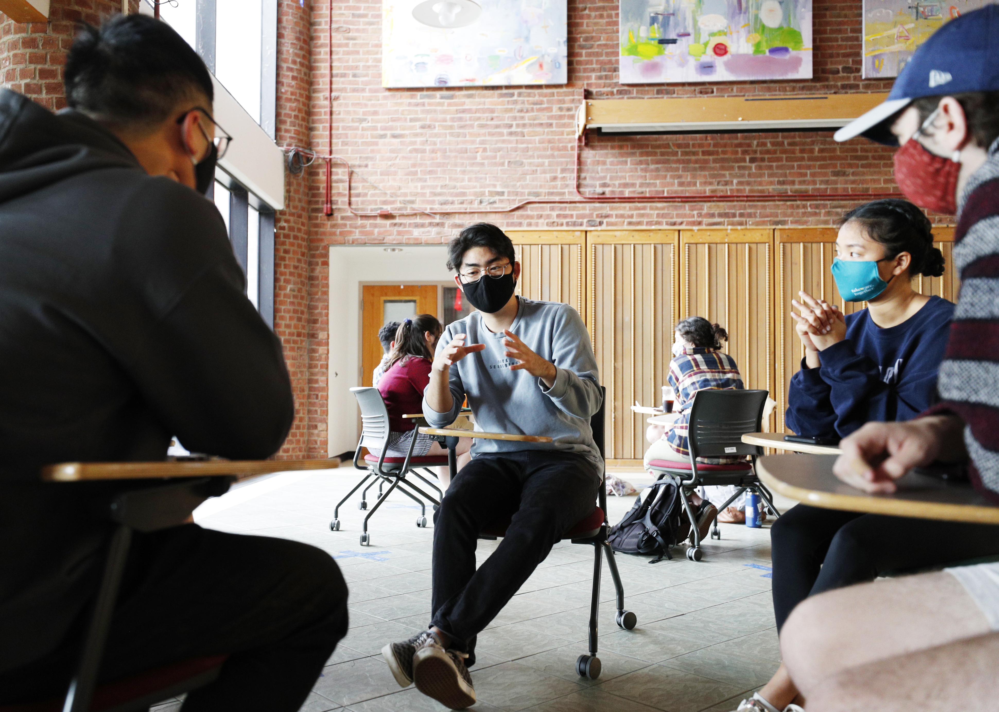 College students gather from individual desks to discuss research