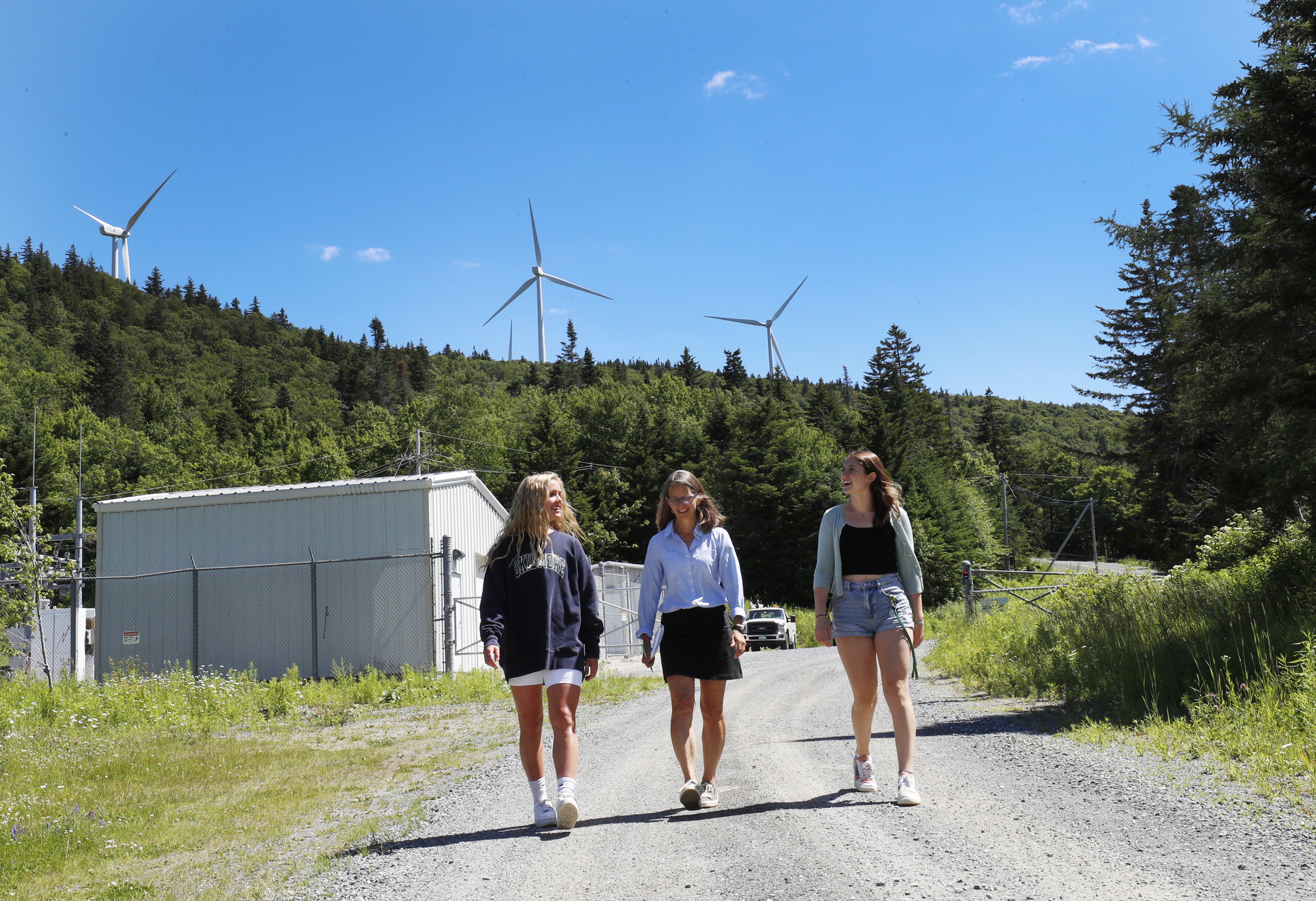 Karen Kellogg, associate professor of environmental studies and sciences, center, talks with Skidmore College students Paige Karl  ’23, left, and Chloe Faehndrich ’23 at a wind farm in Vermont as part of the summer collaborative research program.  