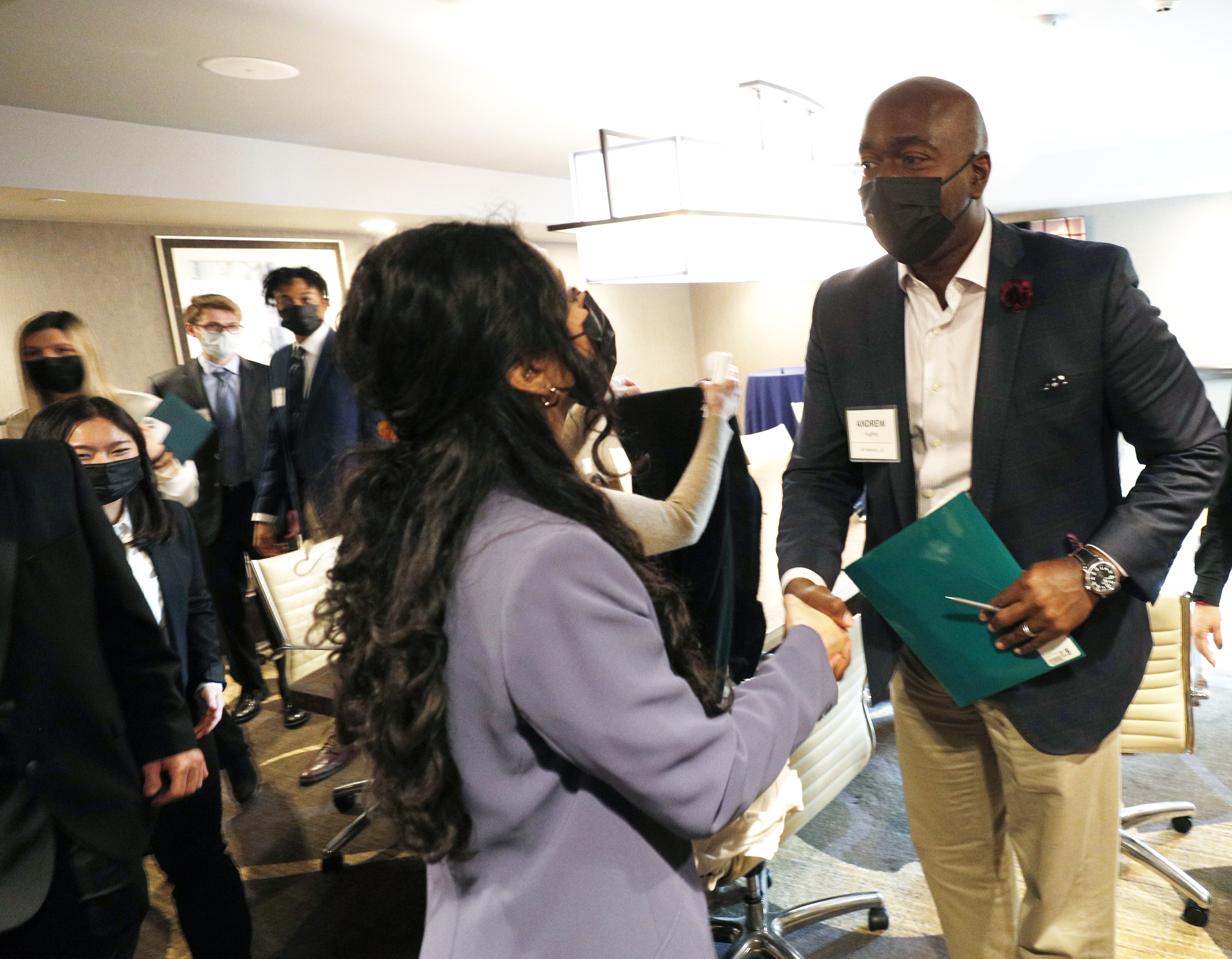 First-year student Sritha Ravi ’25 shakes hands with alumnus Andrew Hughes ‘92, who served on the panel of executives, for the executive presentation.  