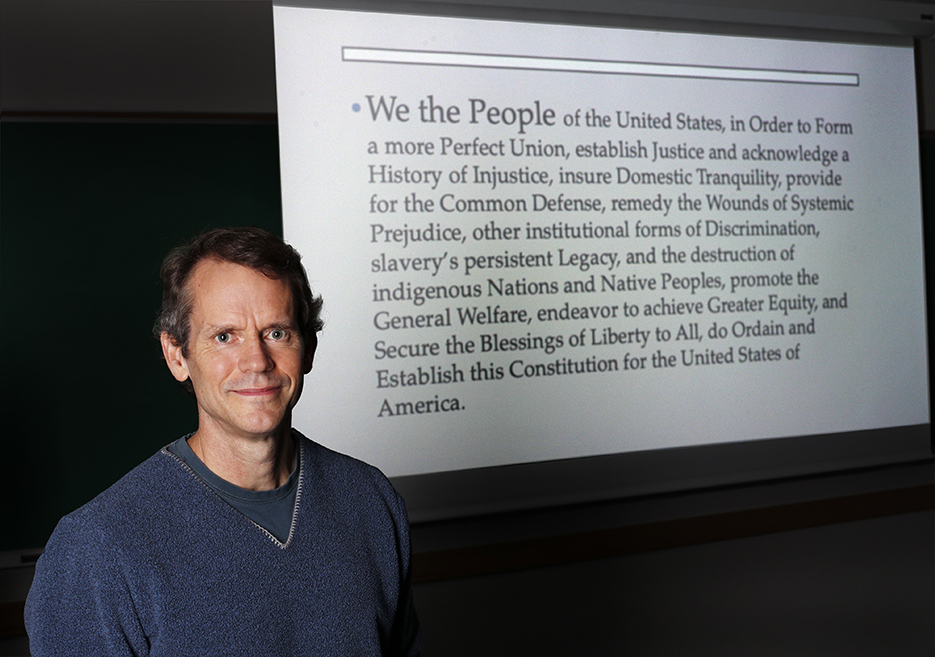 Beau Breslin stands in front of the preamble for his fictitious 2022 constitution.