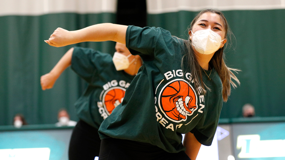 Female dancers perform during a basketball halftime show wearing green t-shirts that say "Big Green Scream" 