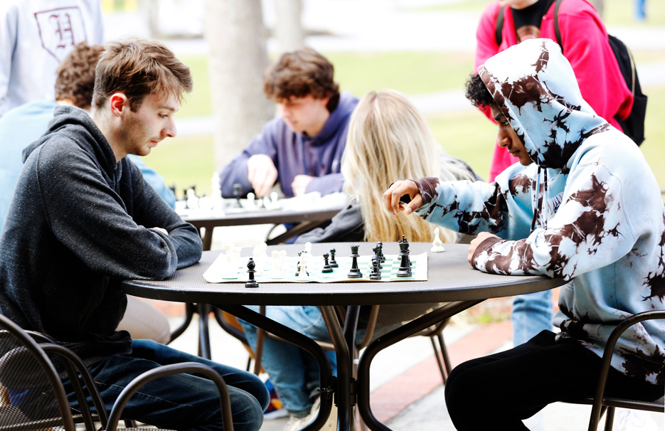 Charlie Davidson ’22 and Arjun B K ’25 play chess on the Case Center patio. 