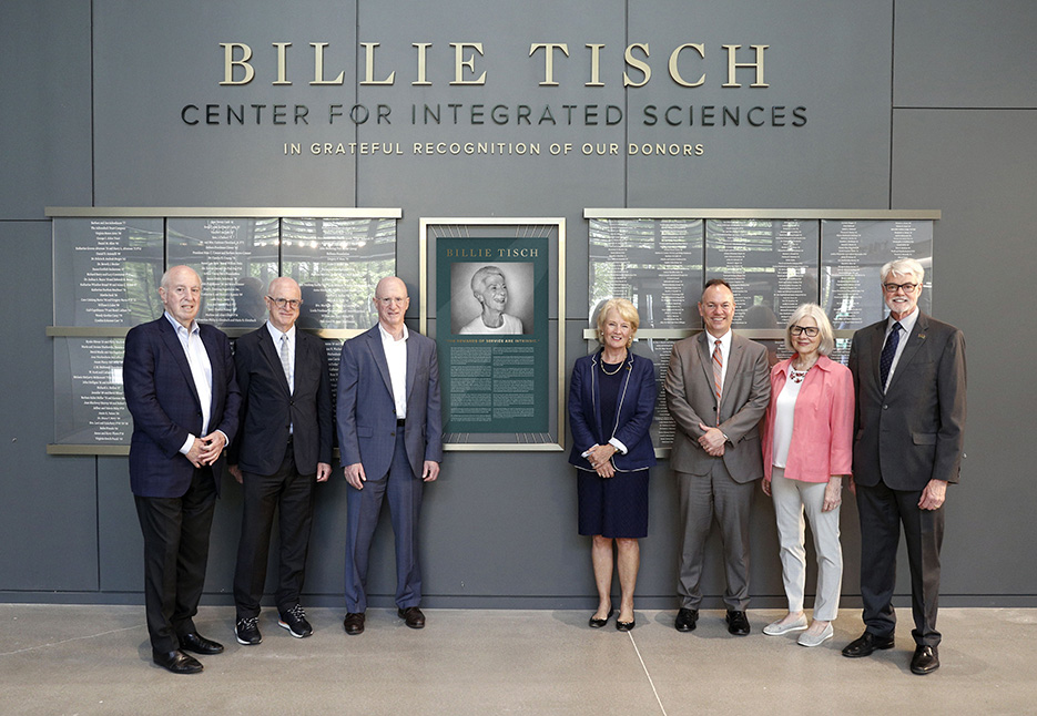 From left, Billie Tisch’s sons Daniel, Thomas, and James Tisch, Chair of Skidmore’s Board of Trustees, Nancy W. Hamilton ’77, President Marc Conner, Marie Glotzbach, and President Emeritus Philip A. Glotzbach stand in front of a donor wall and plaque of beloved alumna Billie Tisch ’48 in the new Billie Tisch Center for Integrated Sciences.  