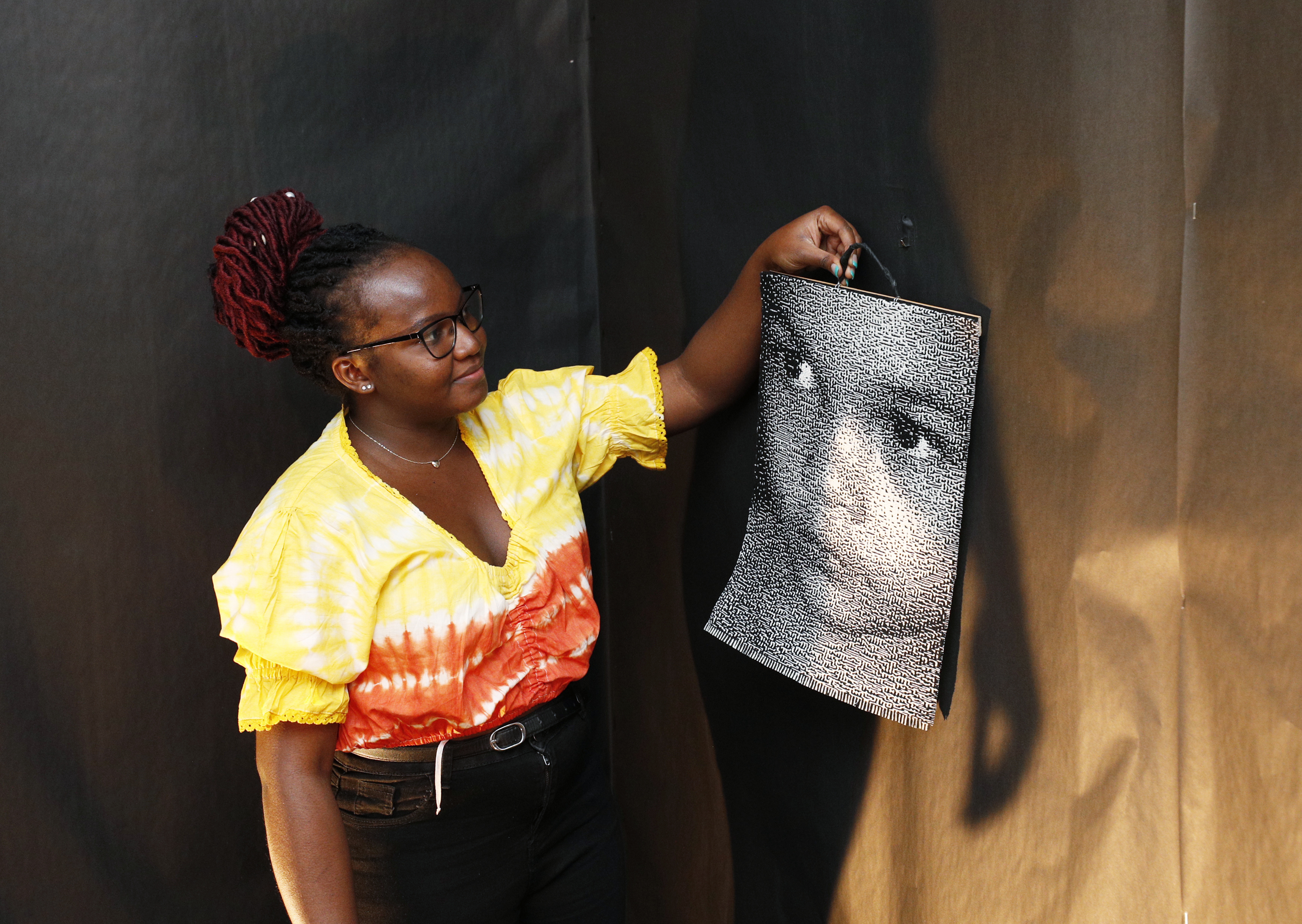 A student hangs artwork 