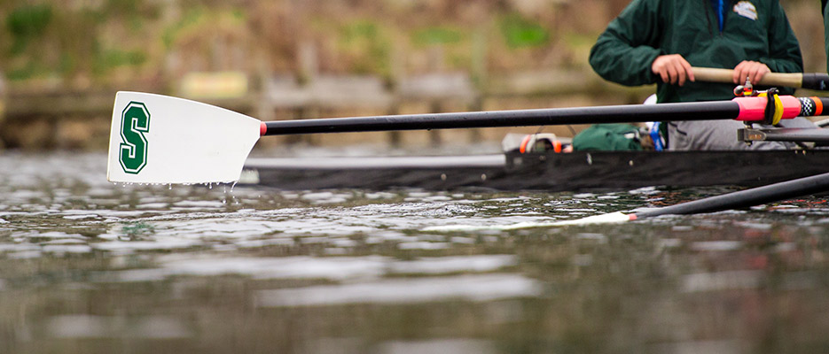 Zoomed in shot of an oar as a college crew team practices rowing