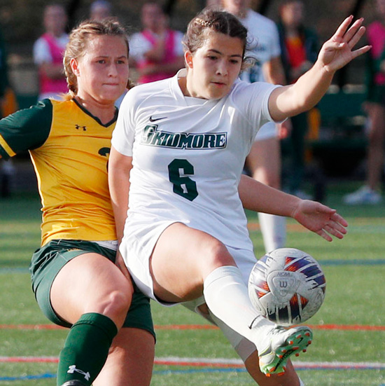 two+women%27s+soccer+players+compete+for+the+ball%2C+one+is+mid-kick