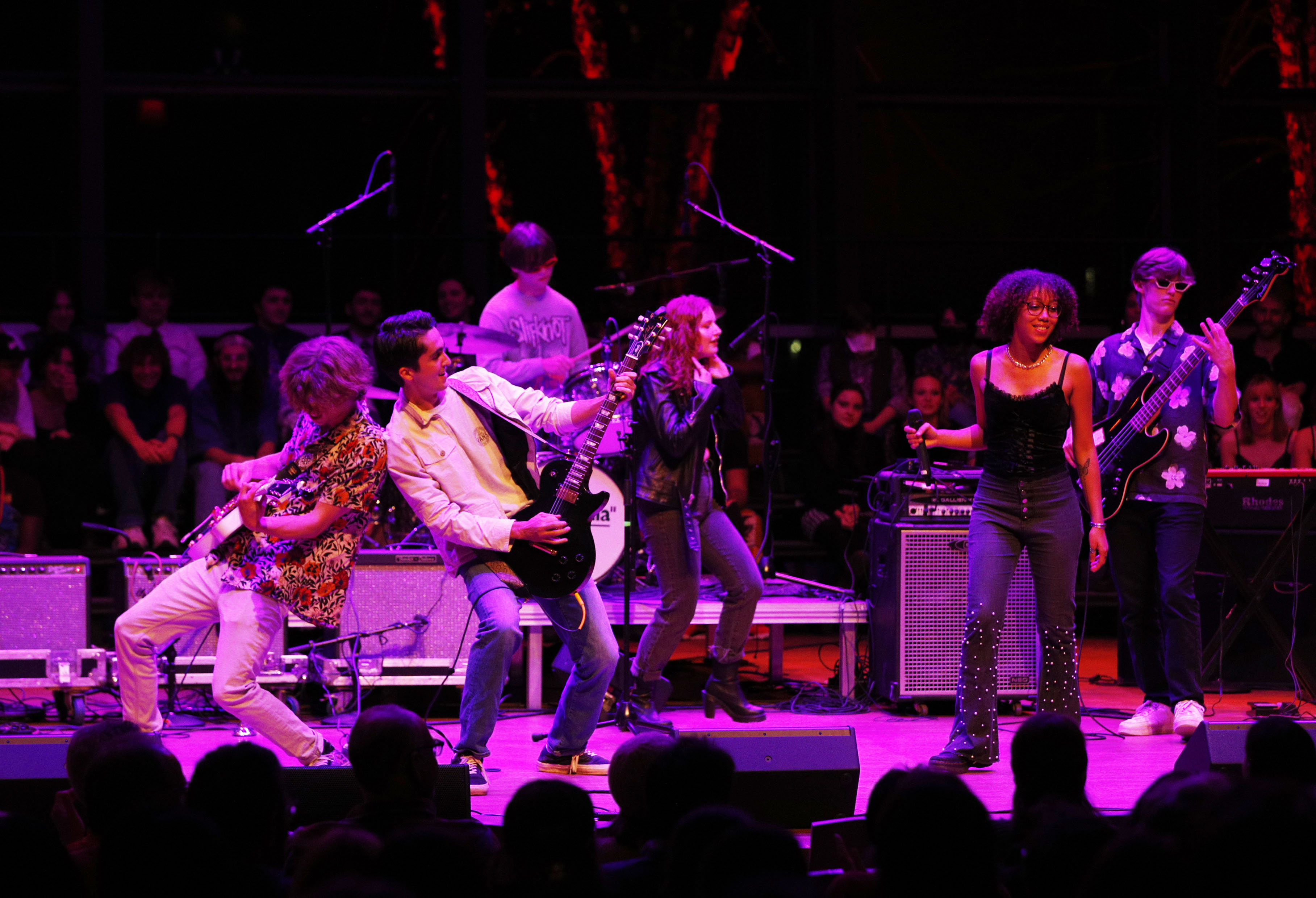 college students perform on stage during a concert under purple lights