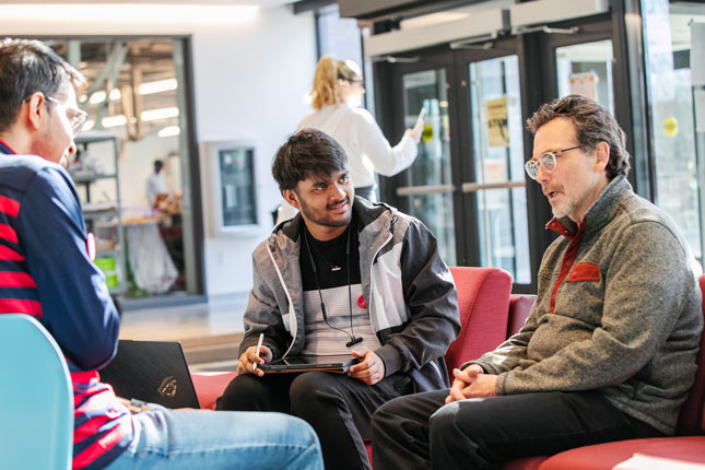 From left, Azizul Hakim '26 and Ankit Gupta '26 talk with Guy Mastrion, F. William Harder Chair in Business Administration, during StartUp Skidmore on Feb. 18 in the Billie Tisch Center for Integrated Sciences.