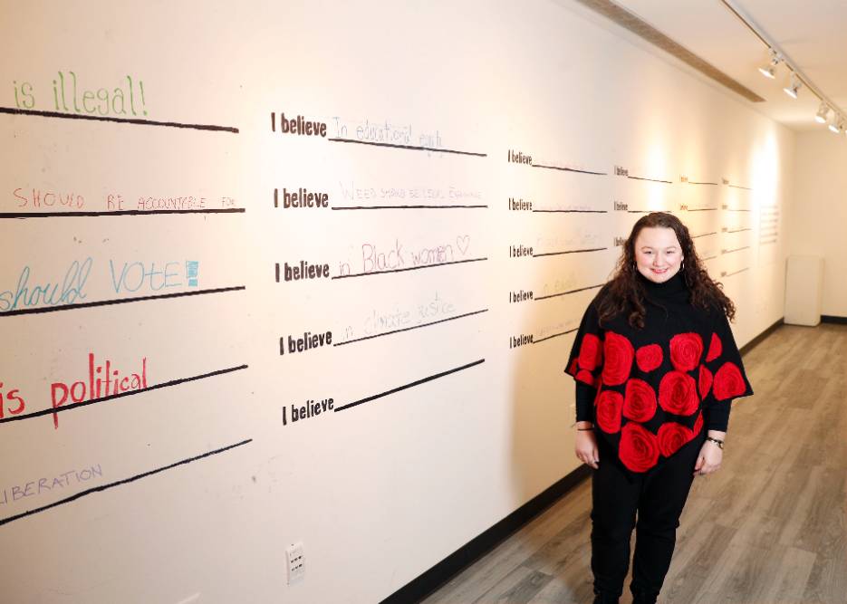 Melanie Nolan '23, who will discuss “Unpacking the Solidarity Project; Art, Shock and Free Speech” as a student panelist at the Speech and Expression on College Campuses Symposium, stands in front of the interactive exhibit she curated in the art gallery in Case Center during the fall semester. 