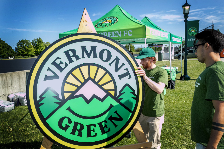 Vermont Green co-founder Matthew Wolff ‘12 places the club’s crest, which he designed, near the Virtue Field entrance.