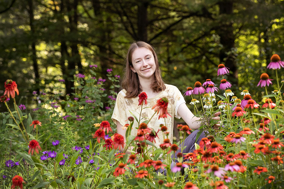 Camilla Brown '24 sits smiling in a field of flowers.