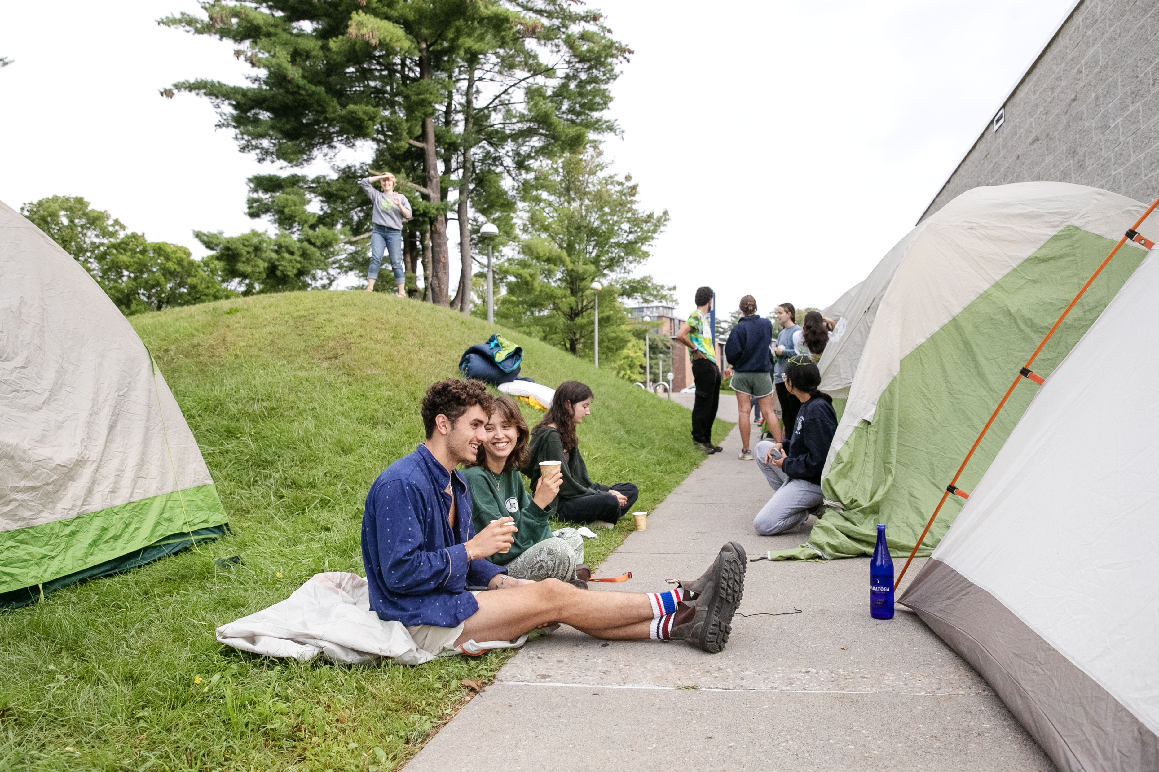 A few students enjoy a morning coffee on the lawn outside the Tang, tents can be seen.