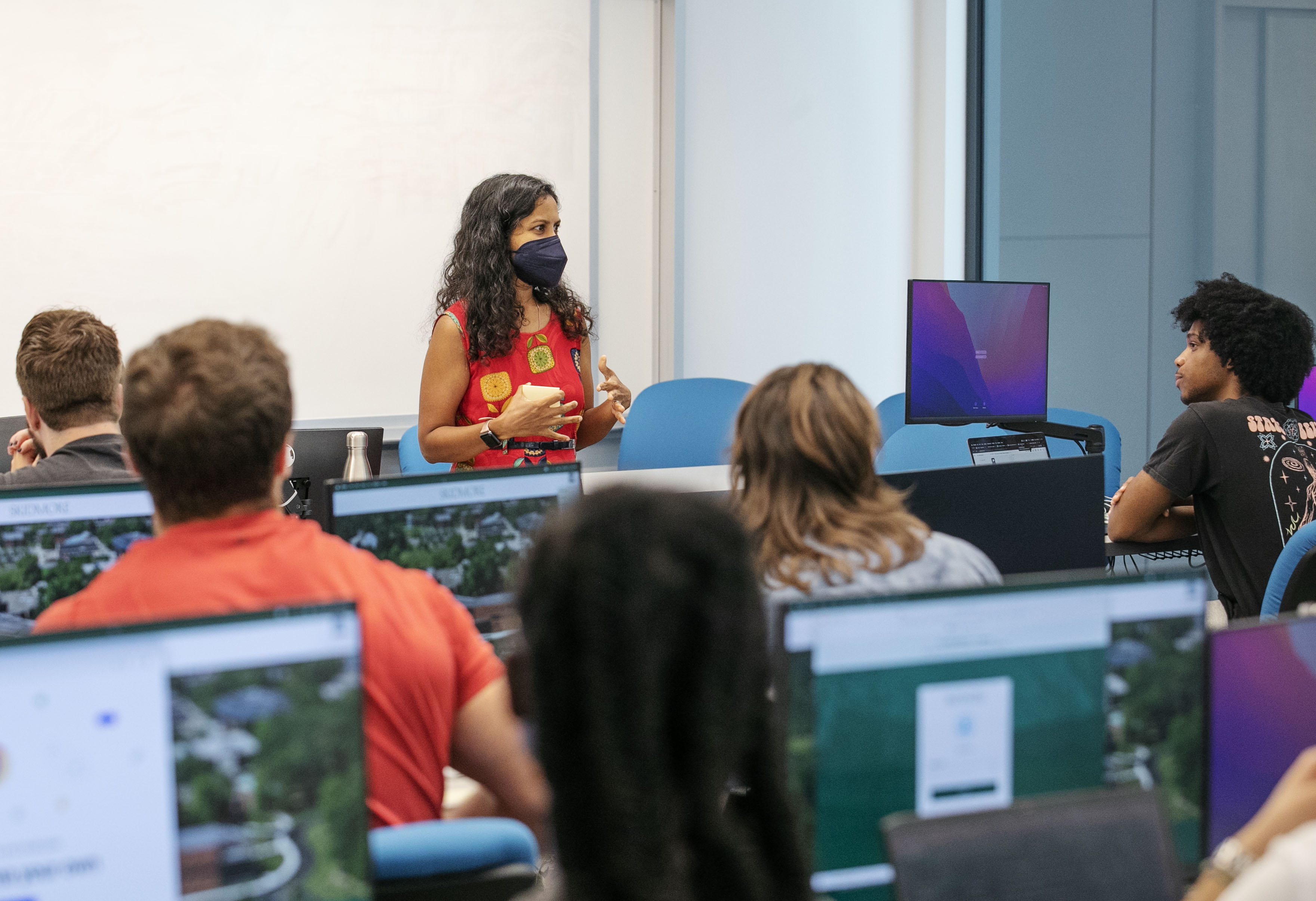 Students watch attentively from behind a row of computers as Aarathi Prasad leads a Mobile Computing course.