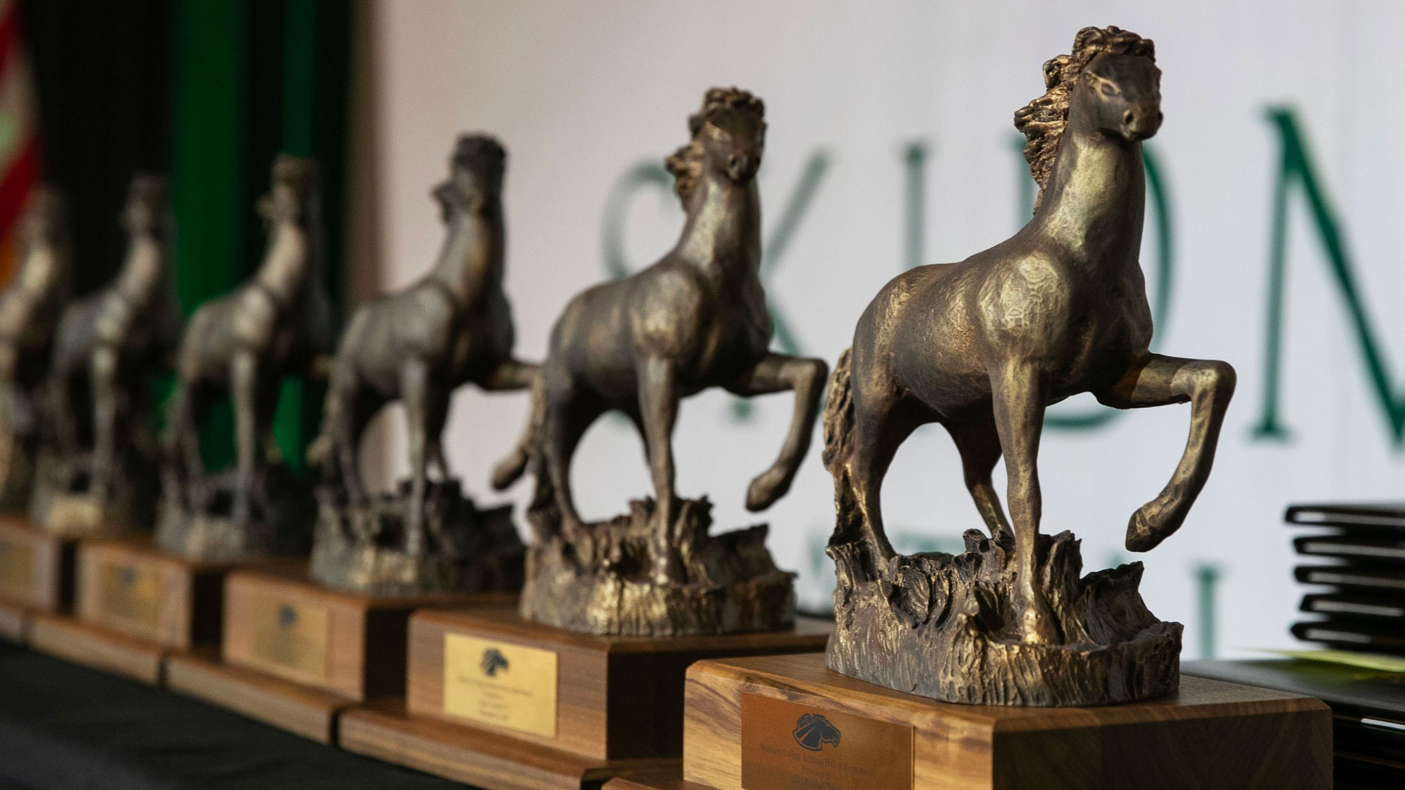a line-up of trophies topped with a horse in motion on a stage awaiting distribution to hall of fame honorees