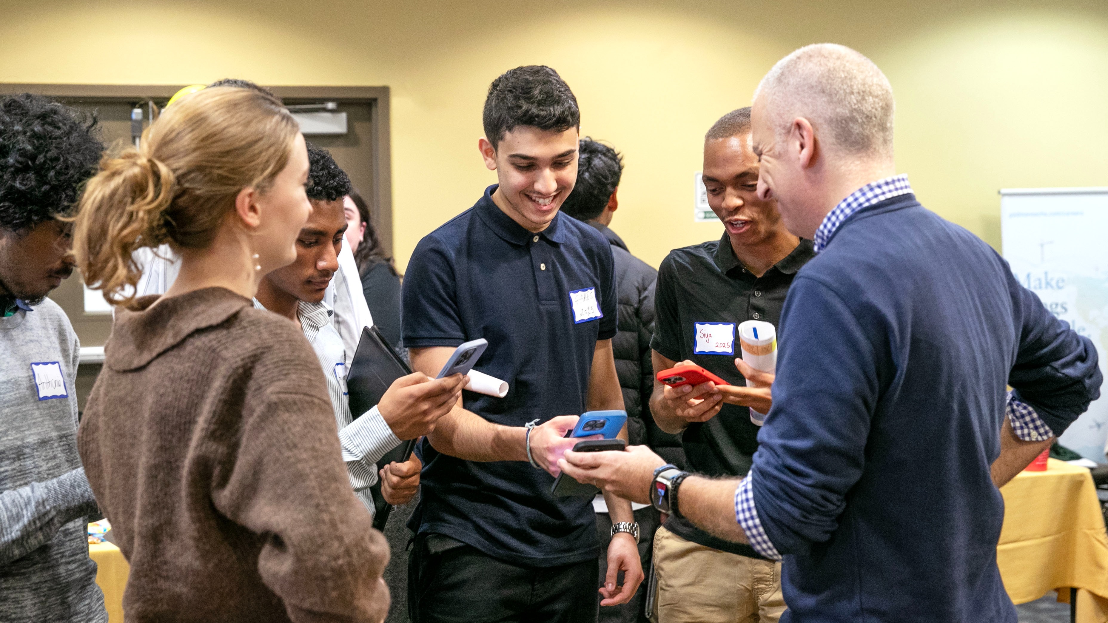 Four students hold out their phones to scan a QR code on a volunteer mentor's phone.