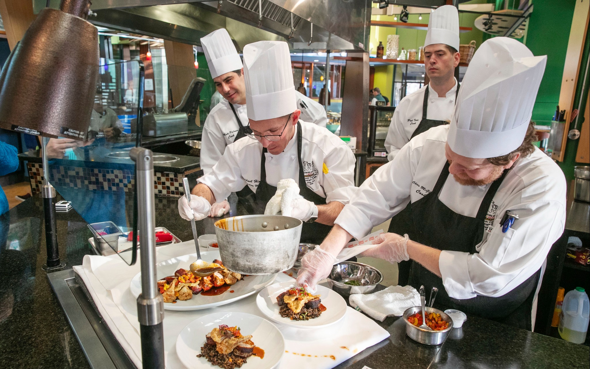 The team prepares their buffet dish, bacon wrapped pork loin.