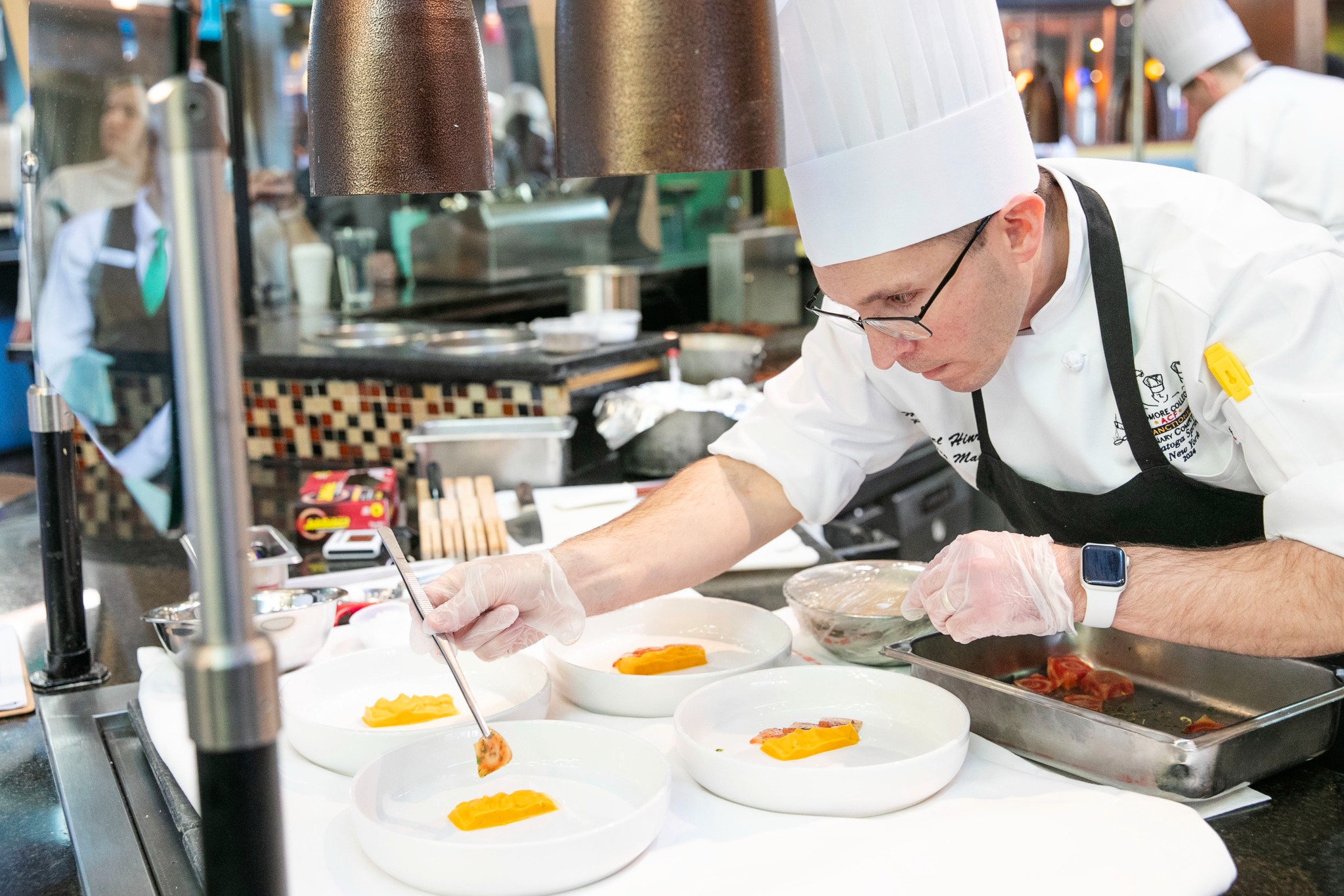 Production Manager Michael Hinrichs, who joined Skidmore in 2023, plates the team's appetizer, pan roasted bronzini.