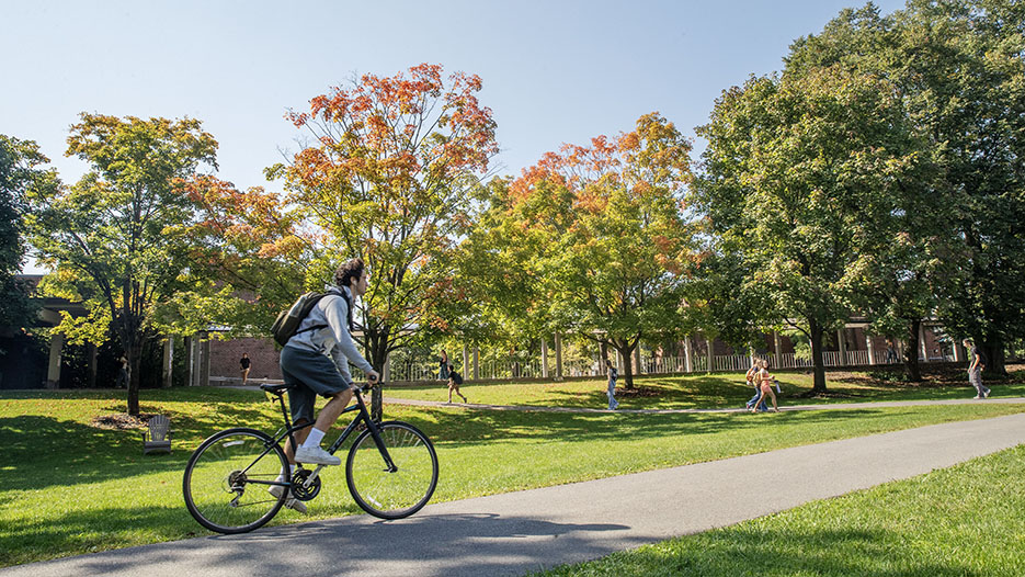 A student bikes across Skidmore's campus in the fall