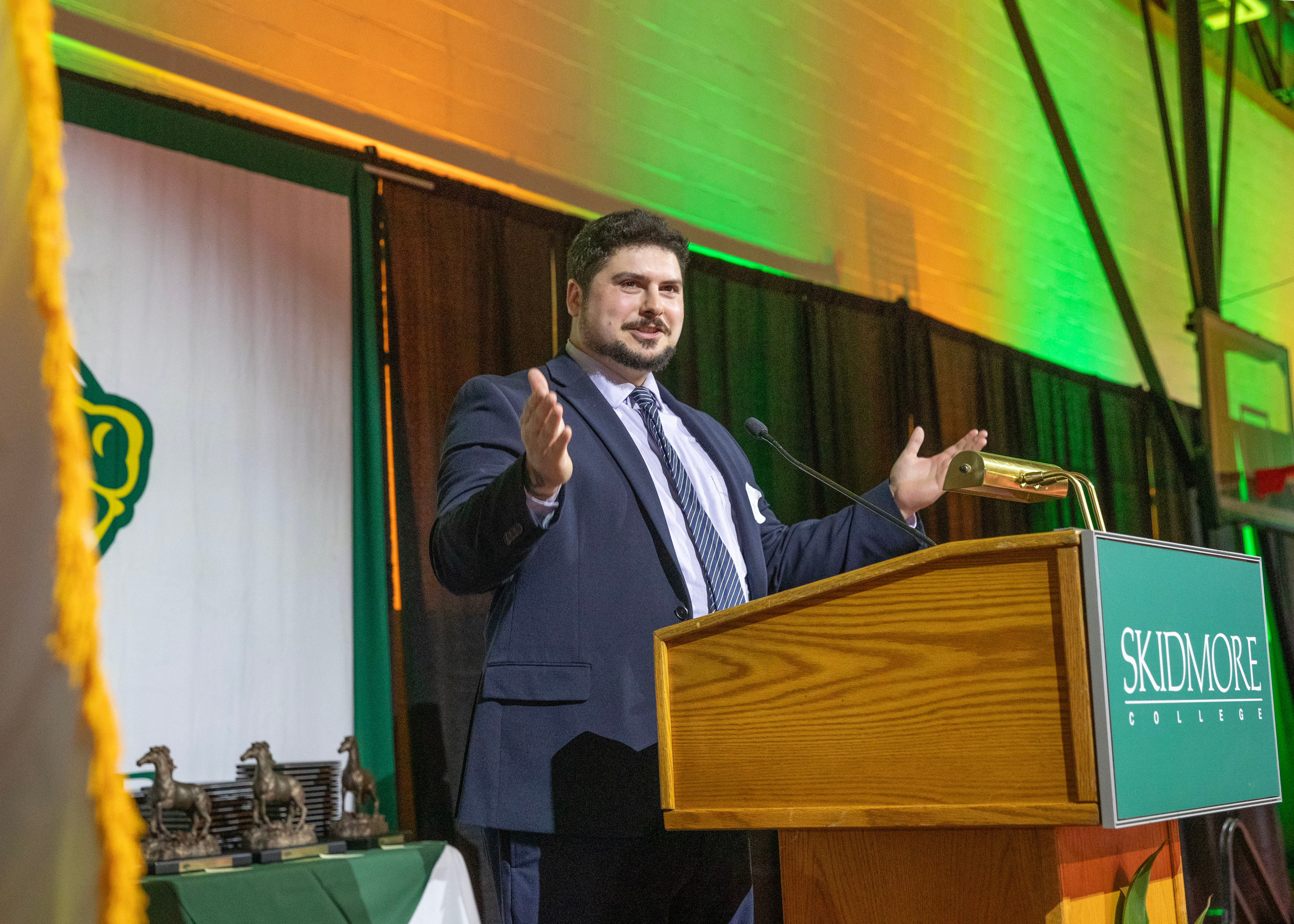 Nicholas Laracuente ’11 Nicholas Laracuente ’11 talks at the podium, gesturing with his arms out.