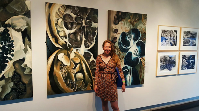 Catherine Headrick ’17 stands in front of two paintings shown as part of her senior thesis exhibition at the Tang Teaching Museum.