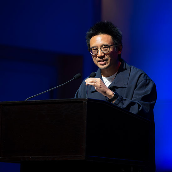 Author+Hua+Hsu+stands+at+a+podium+and+speaks+to+an+audience.
