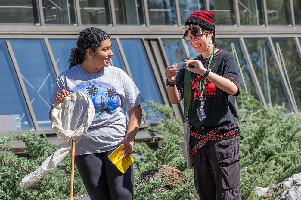 Ashley Cardona ’29, left, and Vanessa Tang ’29 smile as they examine an insect