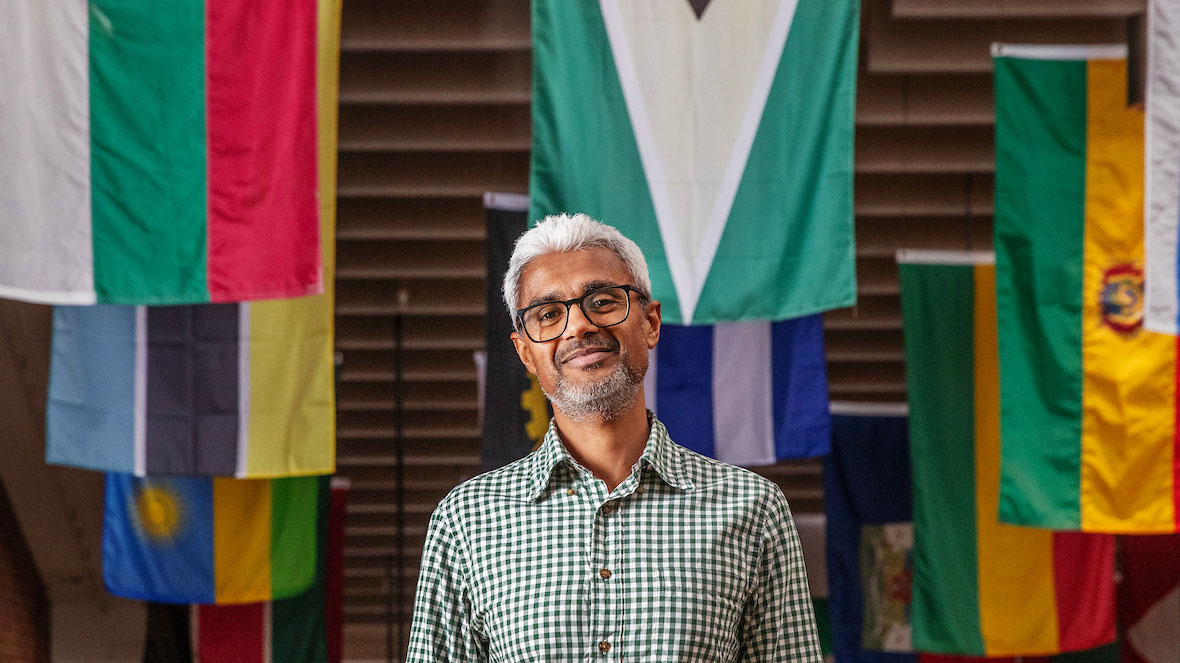 Mahesh Shankar in front of flags in Skidmore's Case Center 