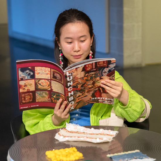 A+student+reads+the+latest+issue+of+Lunchbox+Magazine+while+sitting+at+a+small+table+in+the+Tang+Teaching+Museum
