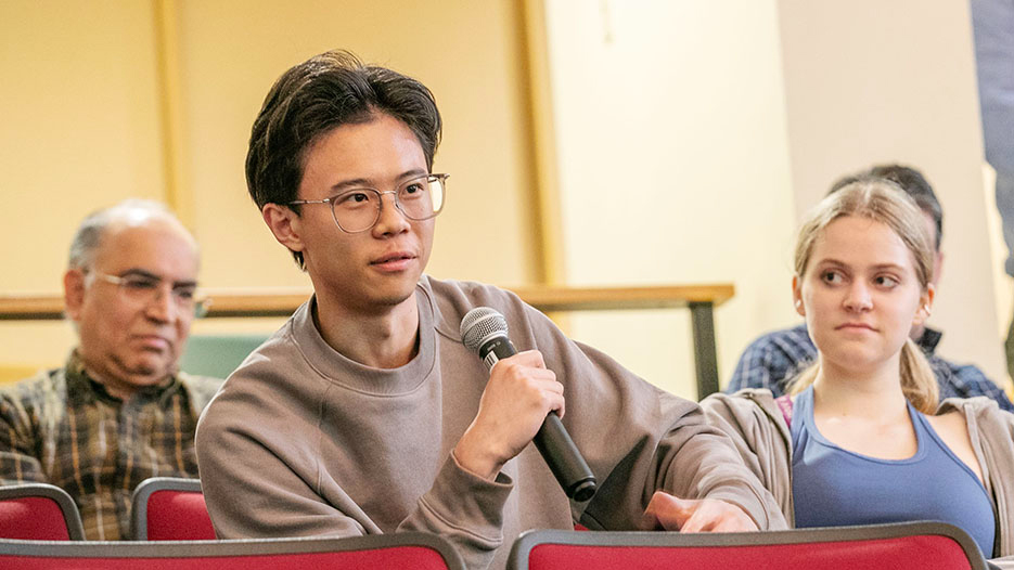 A student holds a microphone to ask a question during a campus event on free speech