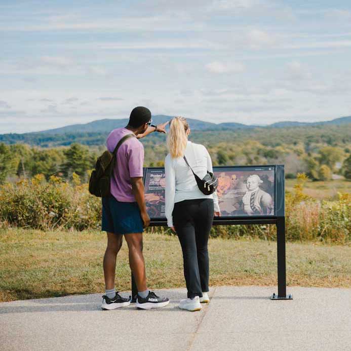 Two+visitors+look+out+over+rolling+hills+and+the+Hudson+River+from+a+scenic+overlook+at+Saratoga+National+Historical+Park.
